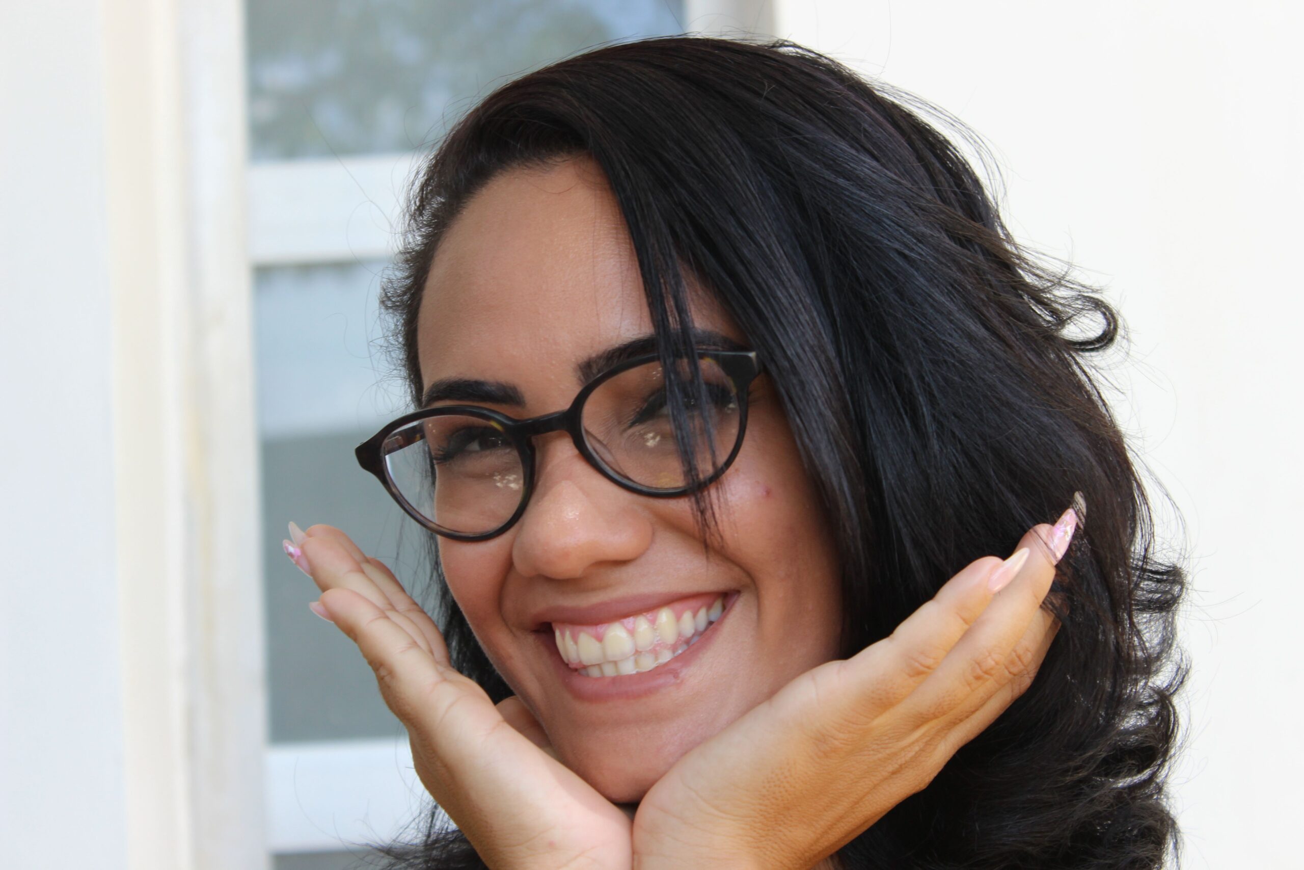 Close-up portrait of a smiling woman with glasses in Camaguey, Cuba, showcasing joy and positivity.